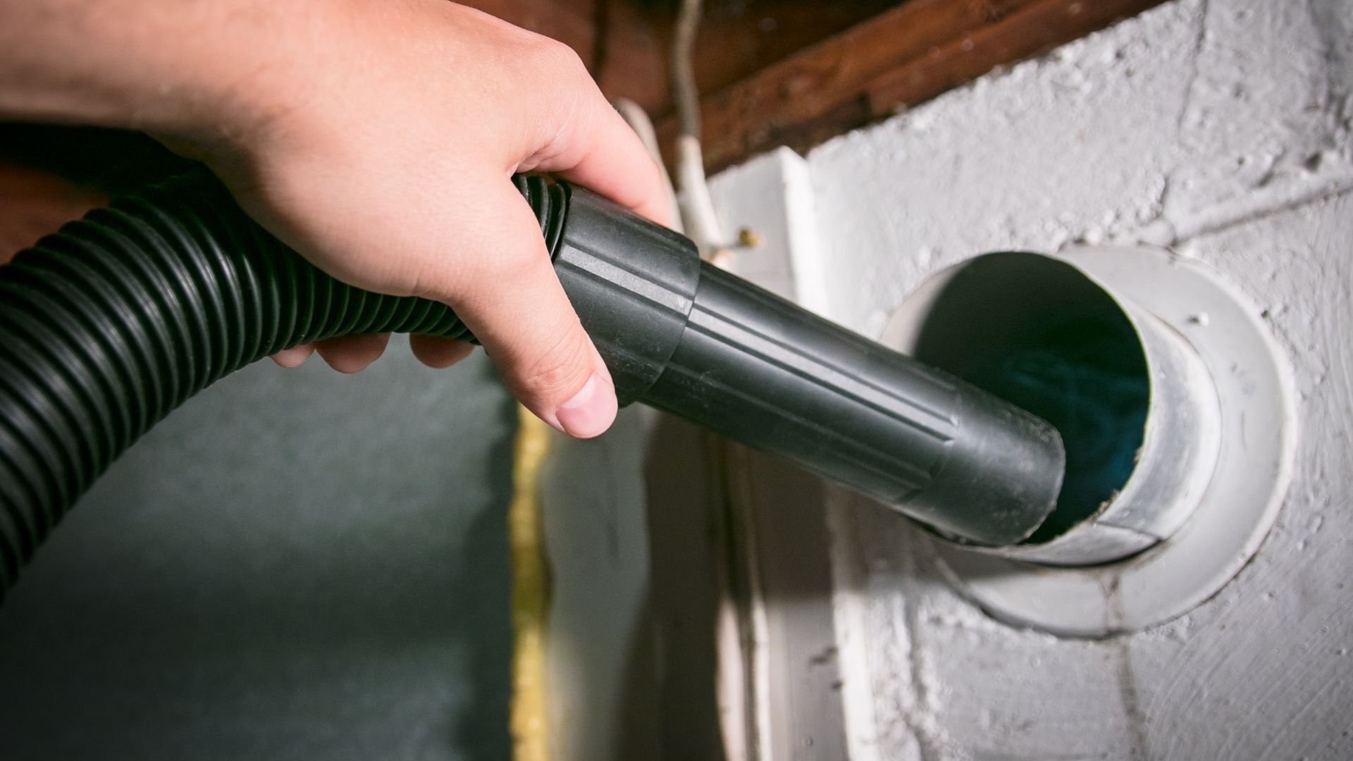 Vacuum cleaner hose attached to wall vent for cleaning or ventilation