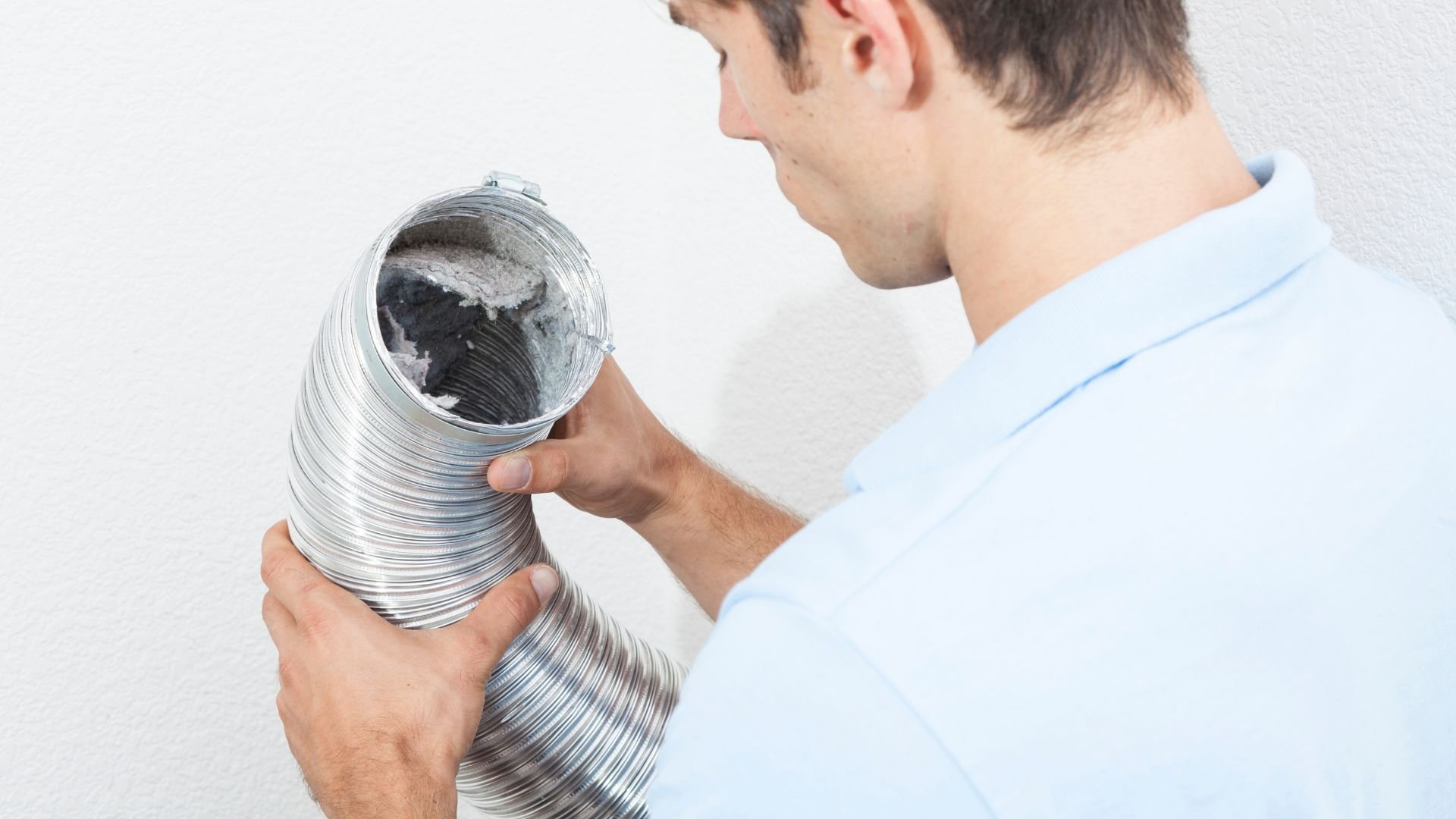 Person examining flexible metal dryer vent duct with dust inside